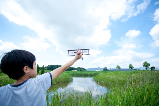 아이가 모형비행기를 들고 습지에 서있는 사진